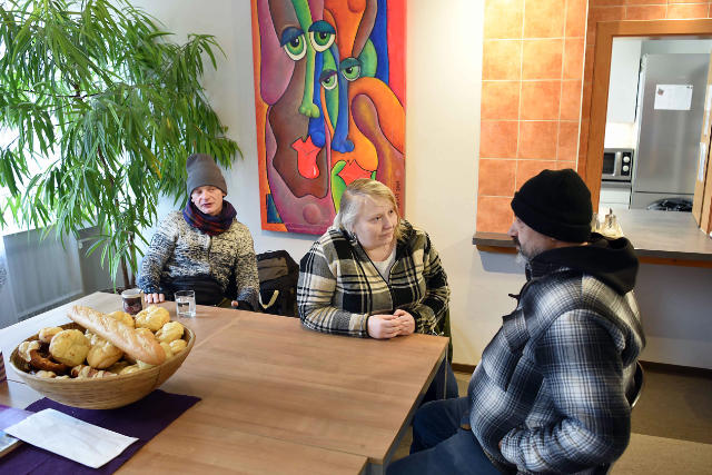 Menschen in einer Tagesstätte, die gemeinsam an einem Tisch sitzen und sich unterhalten